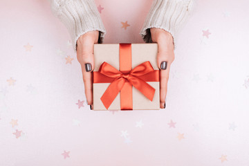 Gift box with bow in woman's hands. Coral - Color of 2019.