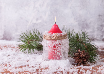 Red candle, twigs and cones on a snow-covered wooden background - 239587828