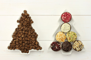 Two dish-spruces with roasted coffee beans  and set of chocolates on the white wooden background