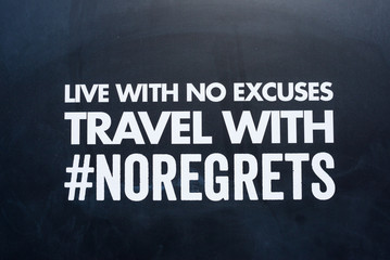 Fototapeta na wymiar Live with no excuses travel with no regrets message written on capital white letters on a black background. #no regrets hashtag