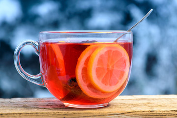 Fruity tea with lemon circles in a glass mug. Winter background, close-up.