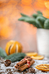 Cinnamon sticks and orange slicesChristmas arrangement with Norwegian pine Nobilis and decorated with toys. Garland bokeh on background. Dark wooden table sprinkled with snow