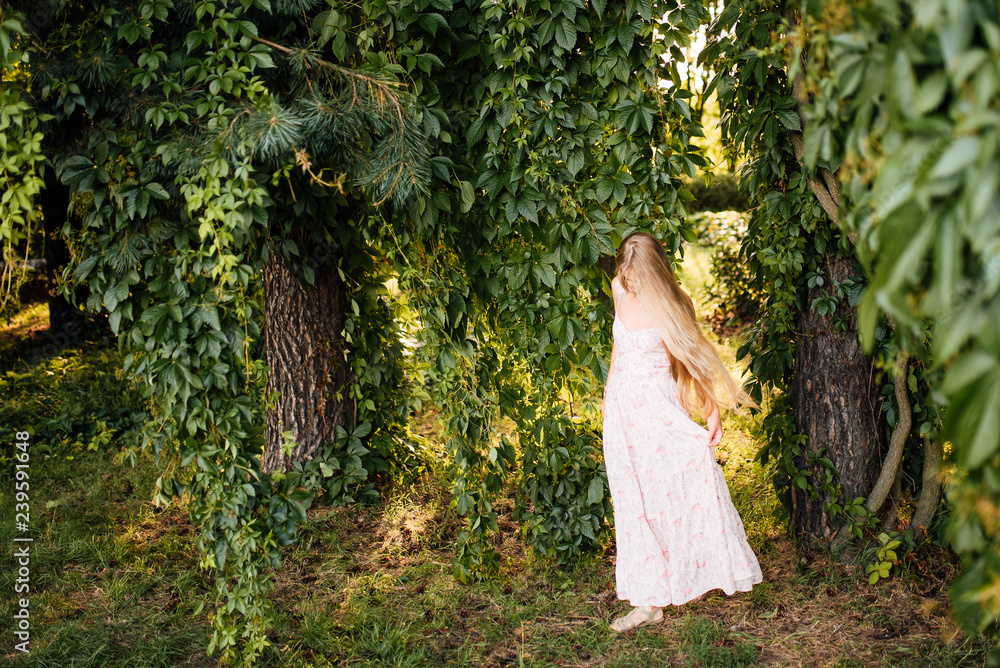 Wall mural beautiful young girl in a white dress with long hair resting outdoors, amazing woman walking in the 