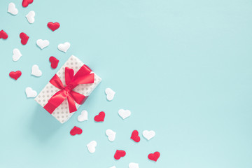 Elegant composition for Valentine's Day. Gift box with red bow, white, red satin hearts on pastel blue background. Valentine day concept, design. Flat lay, top view, copy space