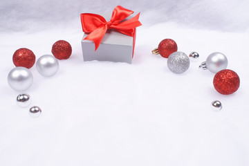 Present and Christmas baubles on snow.