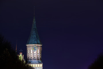 Fototapeta na wymiar clock tower of the old gothic church illuminated by spotlights at night