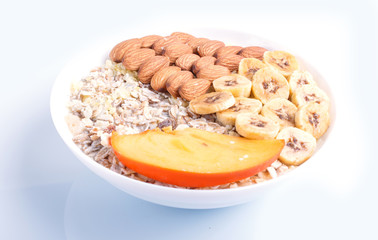 A plate with muesli, almonds, banana, persimmon isolated on white background.