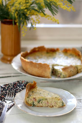 Slice of homemade quiche filled with cheese, ham and leek. Selective focus.