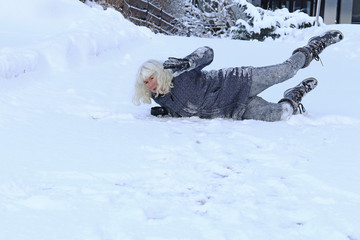 Eine Frau ist auf einer schneebedeckten glatten Straße ausgerutscht und hingefallen