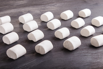 set of marshmallows on black wooden background. geometric pattern.