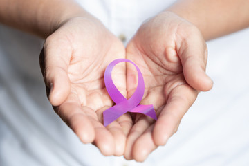 Womans hands holding purple domestic violence awareness ribbon, healthcare and social problems...