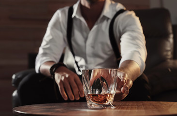 Man with glass of whiskey sitting at table, closeup
