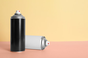 Cans of different spray paints on color background. Space for text