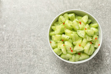 Delicious cucumber salad in bowl on grey background, top view. Space for text