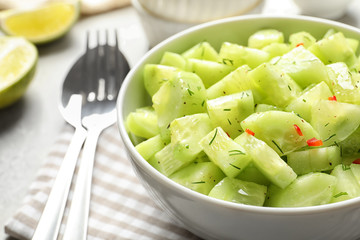 Delicious cucumber salad in bowl on table, closeup