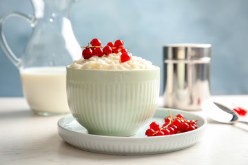 Creamy rice pudding with red currant in bowl on table