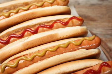 Tasty hot dogs on wooden board, closeup