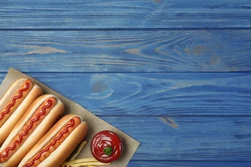Zelfklevend Fotobehang Composition with hot dogs, french fries and sauce on color wooden table, top view. Space for text © New Africa