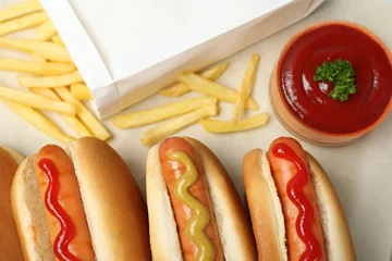 Fotobehang Composition with hot dogs, french fries and sauce on parchment paper, top view © New Africa