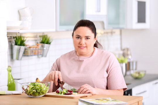 Overweight woman preparing salad in kitchen. Healthy diet