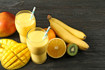 Tasty tropical drink with mango and fresh fruits on wooden table