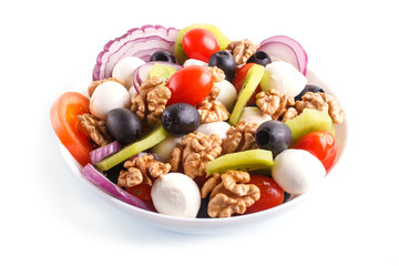 Salad with cherry tomatoes, mozzarella cheese, black olives, kiwi, and walnuts isolated on white background.