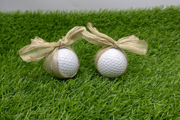 Golf ball with golden ribbon are on green grass