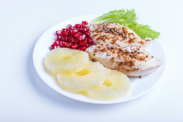 Fried chicken fillets with lettuce, pineapple and pomegranate seeds isolated on white background.