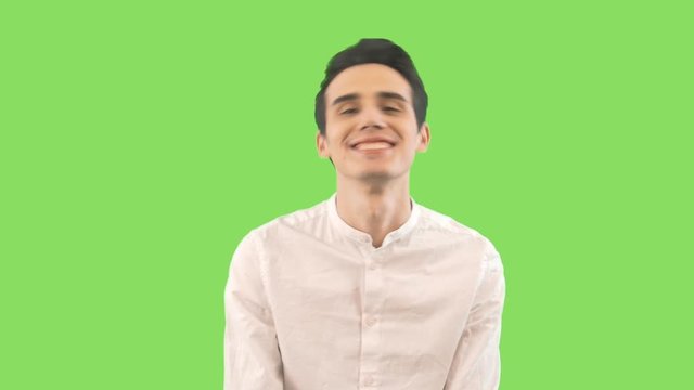 Handsome young man doing different flirty expressions and looking at camera isolated on the green background