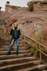 Young Beautiful Modern Caucasian Woman Smiling While Traveling to Red Rocks Park in United States Outside in Nature at the State Park with Ancient Stone and Blue Sky Background