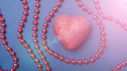 Obraz premium red heart on a blue paper background with red beads and flare flare. The concept of the day of lovers, Valentine's Day Copy Space
