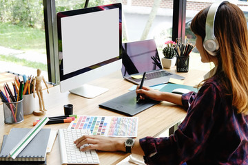 Young female designer drawing sketches on digital graphic draw tablet at studio.