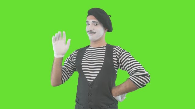 Happy mime showing thumbs up. Cheerful behavior and broad smile of a male actor during the pantomime show. Isolated on green background.