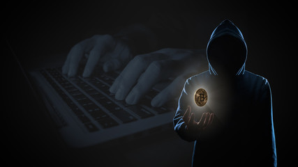 Golden Bitcoin floating above of hacker's hand in dark on hacker hacking with computer laptop...