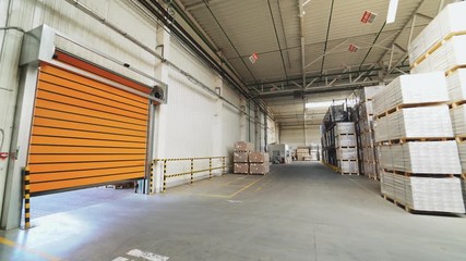 Orange rolling door of the warehouse is closing. Rolettes work with the help of automation. Motion of rolling door to down - Powered by Adobe