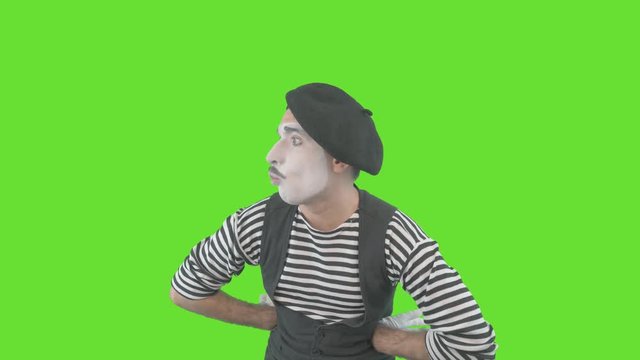Happy mime showing thumbs up. Cheerful behavior and broad smile of a male actor during the pantomime show. Isolated on green background.