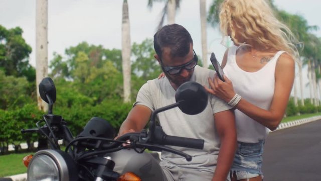 Young woman sitting on motorcycle to his boyfriend