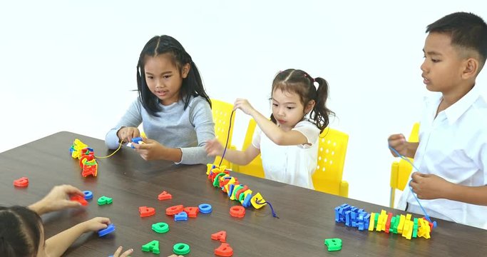 Asian teacher lets Asian student string alphabet toy together, concept for English class.