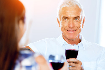 Senior man with holding a glass of wine indoors