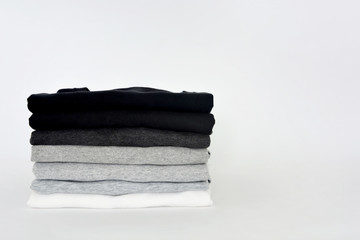 stack of folded black, grey and white color (monochrome) t-shirt on white background, copy space