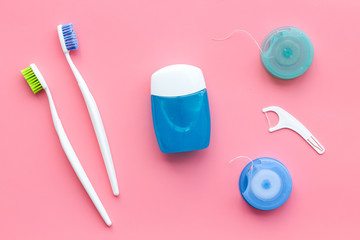 Daily oral hygiene for family. Toothbrush and dental floss on pink background top view