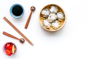 Dinner in Chinese restaurant with dim sum, sticks and tea on white background top view space for text