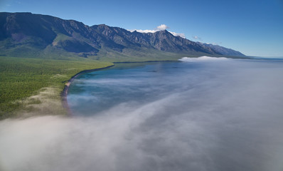 Fototapeta na wymiar Mountain lake scenery with sun shining to the rocky morning mist above the lake