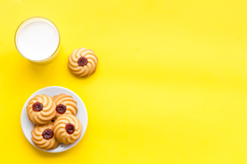 Drink milk with cookies concept. Cup of milk and fresh homemade cookies on yellow background top view space for text