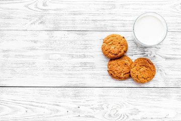 Drink milk with cookies concept. Cup of milk and fresh homemade cookies on white wooden background top view copy space