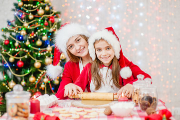 Portrait of a happy family at christmas. Mother teaches her daughter to cook Christmas cookies