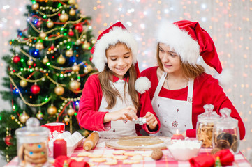 Merry Christmas and Happy Holidays. Mom and daughter in a Christmas hat are preparing a festive treat