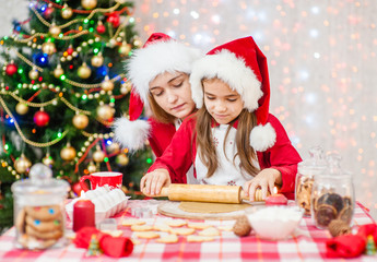 Happy family at christmas. Mom teaches her daughter to cook Christmas cookies