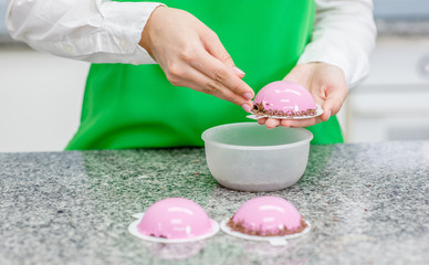 Obraz na płótnie Canvas confectioner decorate small cake with mirror glaze at kitchen
