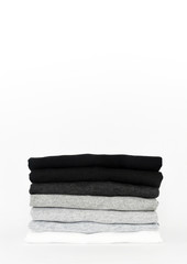 stack of folded black, grey and white color (monochrome) t-shirt on white background, copy space